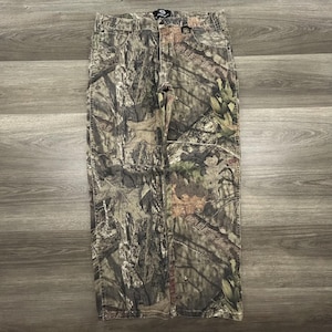 May include: Camouflage-patterned pants in shades of brown, green, and tan. The pants have a classic five-pocket design and a button and zipper closure. The fabric appears to be a durable cotton blend, suitable for outdoor activities.