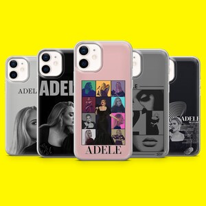 Peut inclure: Plusieurs coques de téléphone représentant la chanteuse Adele. Les coques présentent des images d'Adele dans différentes poses et styles, avec le nom "ADELE" imprimé sur certaines. Les coques sont de différentes couleurs, dont le noir, le blanc et le rose.