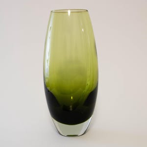 May include: A tall, oval glass vase with a colour gradient. The vase transitions from a dark green base to a lighter green hue towards the top. The vase is transparent, allowing light to pass through.