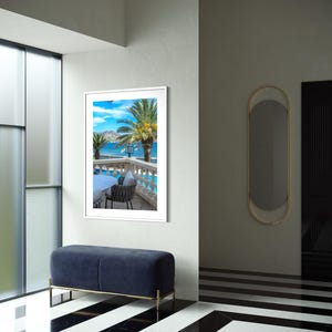 May include: An interior shot featuring a framed landscape print of a coastal scene with palm trees and a blue sky. A navy blue bench with gold legs sits below the artwork. The floor has a black and white striped pattern.