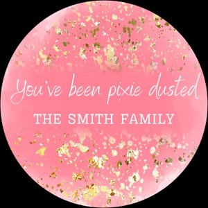 Puede incluir: Gráfico redondo rosa con motas doradas y el texto "You've been pixie dusted" y "THE SMITH FAMILY" en blanco. El fondo tiene un efecto de acuarela.