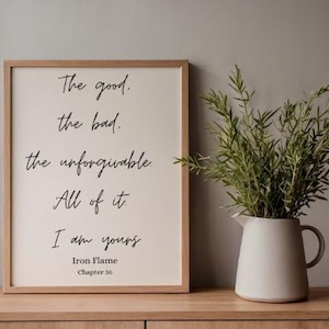 Puede incluir: Un cuadro enmarcado con el texto "The good, the bad, the unforgivable. All of it, I am yours." Una jarra blanca con asa contiene ramas verdes. El marco es de color marr&oacute;n claro y el fondo es neutro.