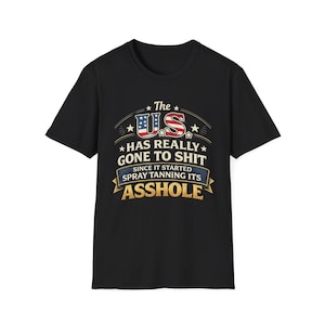 Puede incluir: Camiseta negra con un diseño gráfico. El diseño incluye el texto "The US has really gone to shit since it started spray tanning its asshole" en un estilo patriótico con colores rojo, blanco y azul.
