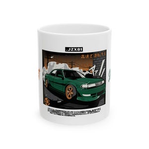 May include: White ceramic mug featuring a green car graphic with gold wheels, smoke, and Japanese text. The mug has the text ".JZX81" at the top. The design is set against a backdrop of a street scene.