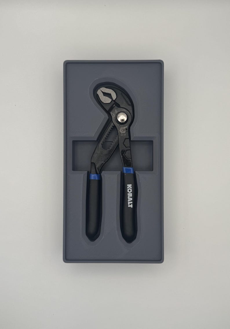 K&ouml;nnte beinhalten: Schwarze und blaue verstellbare Zange mit dem Markennamen "KOBALT" auf dem Griff. Die Zange befindet sich in einem grauen Kunststoffkoffer. Die Zange ist ein Handwerkzeug zum Greifen, Befestigen oder Schneiden.