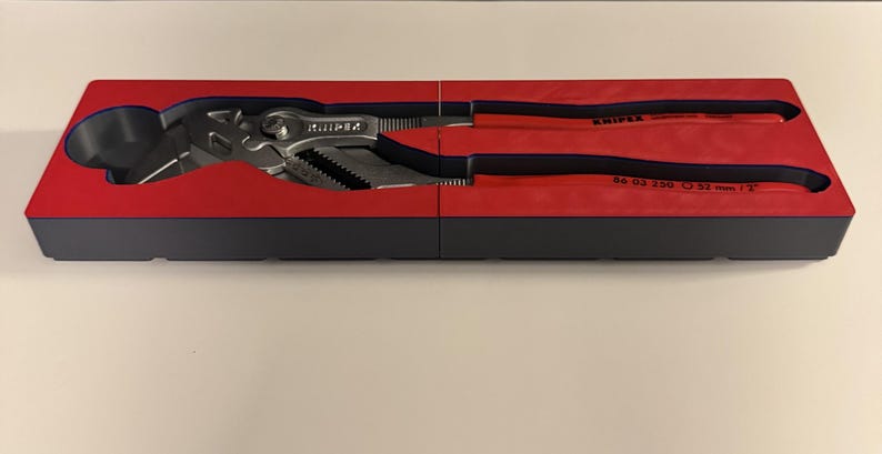Op de afbeelding: Een set Knipex tangen in een rode en zwarte koffer. De tangen zijn zilverkleurig met zwarte en rode handgrepen. De koffer is rechthoekig en verdeeld in twee secties. De tangen zijn ontworpen om te grijpen en te draaien.