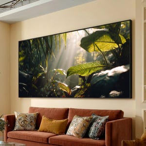 May include: A large framed art print depicting a lush, green jungle scene with sunlight streaming through the leaves. The artwork hangs above a rust-colored sofa with decorative pillows, creating a warm and inviting living space.
