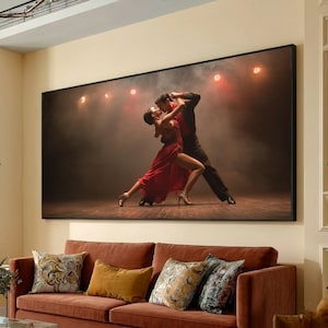 May include: A large framed print of a couple dancing the tango. The woman wears a flowing red dress, and the man is in a dark suit. The background is a smoky stage with red spotlights. The print hangs above a red sofa with decorative pillows.