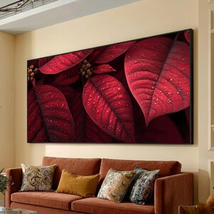 May include: A rectangular canvas print showing close-up of vibrant red leaves with water droplets. The artwork is framed in black and hangs above a brown sofa with decorative cushions. The leaves have a textured appearance.