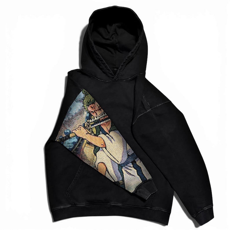 May include: Black hooded sweatshirt featuring a colorful graphic of a character playing a flute. The graphic is on the left side of the sweatshirt. The sweatshirt has a front pocket and a hood.