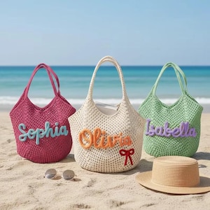 May include: Three crocheted tote bags in magenta, cream, and light green. The magenta bag features the name Sophia in light blue, the cream bag features the name Olivia in orange with a red bow, and the light green bag features the name Isabella in purple.