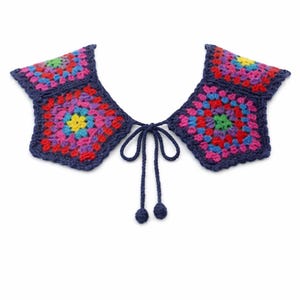 May include: A colorful, crocheted collar with a square design. The collar features a vibrant mix of colors, including pink, blue, yellow, and green, set against a dark blue border. It has a tie closure with two small ball-shaped accents.