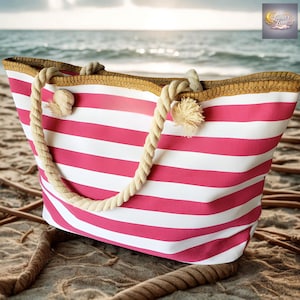 May include: A pink and white striped beach tote bag with rope handles. The bag has a woven trim and is sitting on a sandy beach with the ocean in the background.