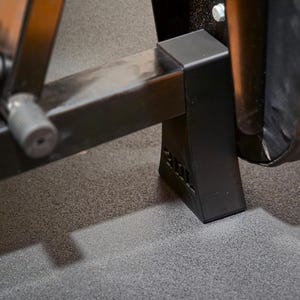 May include: A black metal exercise bench frame featuring a sturdy base support with a molded plastic foot. The structure includes a horizontal beam connected to a vertical leg component, secured with a visible silver bolt and a textured black finish.