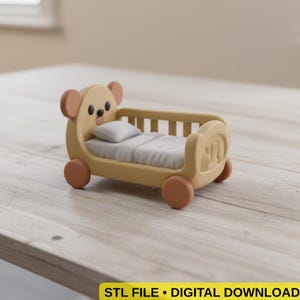 May include: A whimsical, light yellow toy bed shaped like a bear, complete with a small pillow and blanket. The bed has rounded wheels and a bear face design on the headboard. The image includes the text "STL FILE • DIGITAL DOWNLOAD".