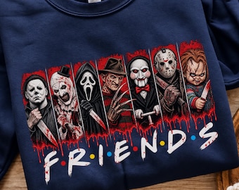 May include: A navy blue crewneck sweatshirt featuring a graphic print of seven horror movie characters standing in individual panels above the text "F R I E N D S" in a white font with red blood-like drips and colorful dots between letters.