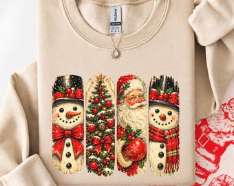 May include: A sand-colored crewneck sweatshirt featuring a graphic print of four vertical panels. The panels display a snowman with a top hat, a decorated Christmas tree, Santa Claus, and a second snowman wearing a red plaid scarf.