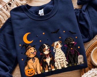 May include: A navy blue crewneck sweatshirt featuring a graphic of four dogs in Halloween costumes. The dogs are dressed as a witch, a vampire, a mummy, and a vampire with a cape, standing near a pumpkin, a crescent moon, and a tombstone.