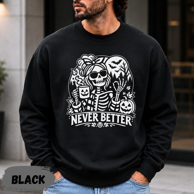 May include: A black crewneck sweatshirt featuring a white graphic print of a skeleton wearing sunglasses and a hair bow, holding a jack-o'-lantern mug. The design includes bats, trees, and the text NEVER BETTER in a bold, stylized font.