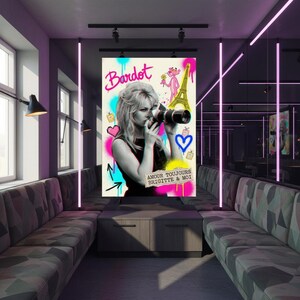 Może przedstawiać: Biały ceramiczny kubek z czarnym uchwytem i napisem "But First, Coffee" pogrubioną, czarną czcionką. Kubek jest ustawiony na rozmytym tle, podkreślając jego czysty design.