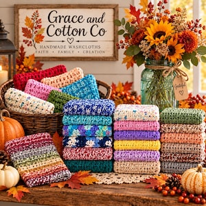 May include: A collection of colorful crocheted washcloths stacked in piles and a wicker basket, accompanied by pumpkins, a glass jar filled with sunflowers and autumn foliage, and a wooden sign reading Grace and Cotton Co.