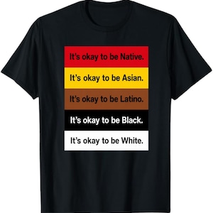 May include: A black t-shirt featuring a central rectangular graphic composed of five horizontal colour bands: red, yellow, brown, black, and white. Each band contains the text 'It's okay to be' followed by Native, Asian, Latino, Black, or White.