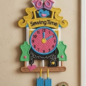 Puede incluir: Un reloj de pared decorativo con temática de costura. La esfera del reloj es rosa con números y manecillas azules. El reloj está rodeado por un marco amarillo con las palabras "Sewing Time". Incluye unas tijeras, una máquina de coser y dos maniquíes.