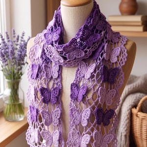 Peut inclure: Une écharpe violette au crochet faite à la main, ornée d'un motif de papillons. L'écharpe est présentée sur un mannequin, mettant en valeur le travail ajouré détaillé et les décorations de papillons en trois dimensions. La palette de couleurs comprend des nuances de lavande et de violet profond.