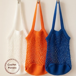 May include: Three crocheted net bags in white, orange, and blue hang against a white wall. The bags have long straps and a mesh design. The image includes a circular graphic that says "Crochet Pattern".