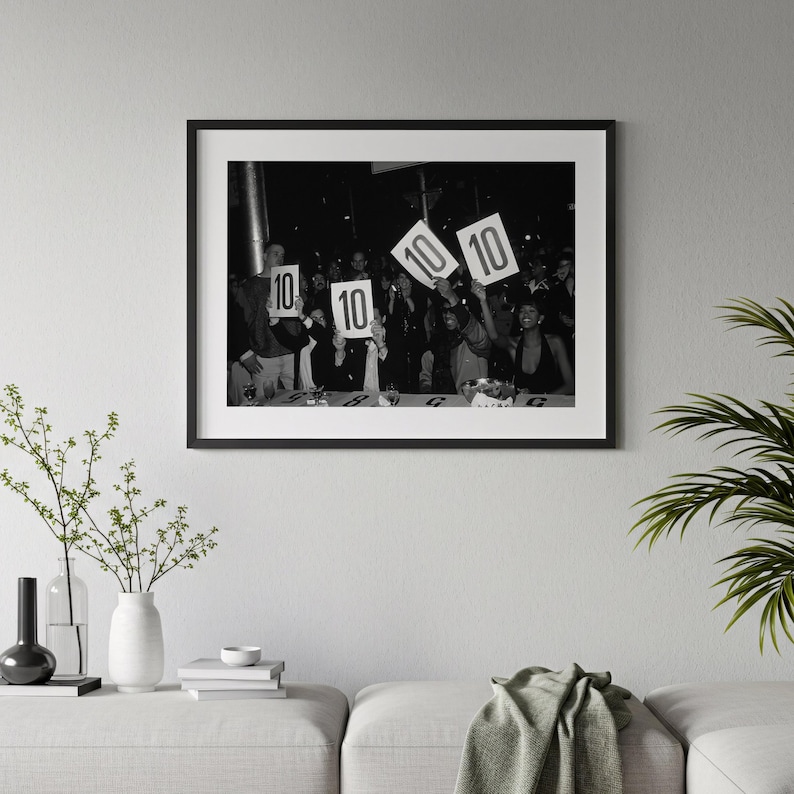A black and white photograph of a group of people holding up signs with the numbers "10" and "10" on them, suggesting a competition or event.