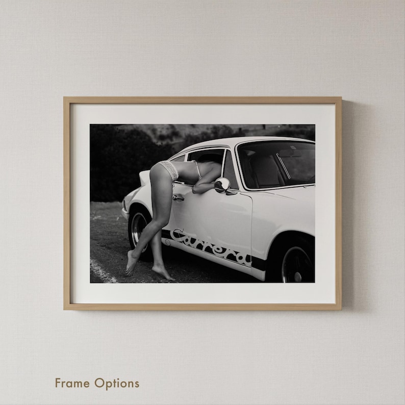 A black and white photograph of a person leaning on a car, with the car's design visible on the side.