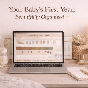 May include: A laptop showing a baby's first-year tracker sits on a desk, with a teddy bear, baby bottle, and wooden toys. The text "Your Baby's First Year, Beautifully Organized" is visible. A wooden calendar shows the date.