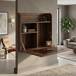 May include: A wall-mounted walnut-toned wooden desk featuring a fold-down work surface supported by two metal struts. The unit includes an upper shelf and two vertical storage compartments, with a dark leather desk pad and a small clock on top.