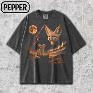 Puede incluir: Una camiseta de manga corta gris carbón con un estampado gráfico de dos fénecs en un paisaje desértico bajo una luna y un cielo estrellado, con la palabra PEPPER en un recuadro negro en la esquina superior izquierda de la imagen.