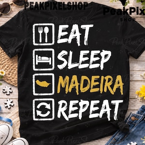 Puede incluir: Una camiseta negra de manga corta con un diseño gráfico blanco de cuatro cuadrados apilados. Los cuadrados contienen iconos de un tenedor y una cuchara, una cama, un mapa de Madeira y dos flechas, seguidos del texto EAT, SLEEP, MADEIRA, REPEAT.