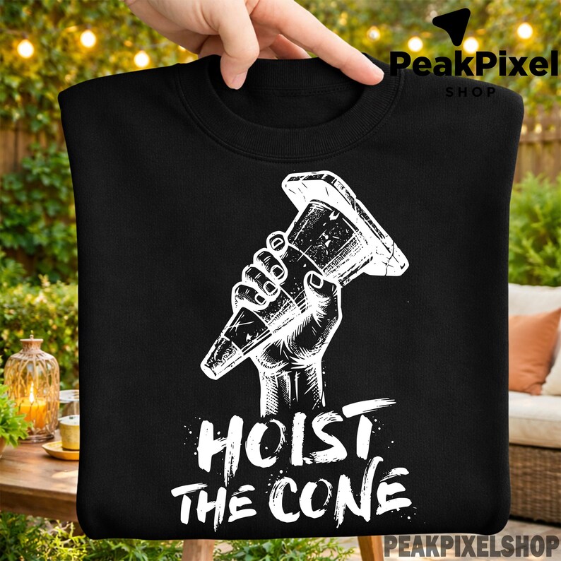 Pu&ograve; includere: Felpa nera con una grafica bianca di una mano che tiene un cono stradale. Il testo "HOIST THE CONE" &egrave; stampato in bianco sotto. La felpa &egrave; tenuta da una persona.