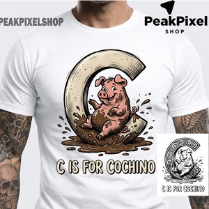 Può includere: T-shirt bianca con un maiale dei cartoni animati nel fango all'interno di una "C". Il maiale è rosa con fango marrone. Il testo "C IS FOR COCHINO" è sotto la grafica. Una versione più piccola in bianco e nero del design è in basso a destra.