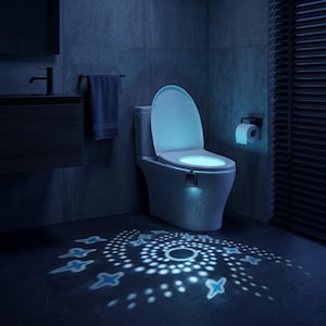 May include: A modern white toilet with a glowing blue light under the seat and a matching blue light on the floor. The floor light projects a spiral design with star-shaped accents. The bathroom has a dark, modern aesthetic.