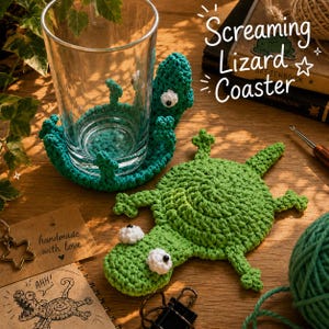 May include: Two green crocheted lizard coasters with white eyes. One coaster is flat, while the other is curved around a clear glass. The text "Screaming Lizard Coaster" is visible in the image, along with a drawing of a lizard and the text "handmade with love".