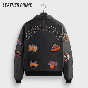K&ouml;nnte beinhalten: Schwarze Lederjacke mit mehreren Aufn&auml;hern mit Basketball-Teamlogos. Auf der R&uuml;ckseite der Jacke steht das Wort "AVIREX" und oben der Markenname "LEATHER PRIME".