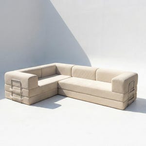 May include: A beige sectional sofa with a corduroy texture. The L-shaped sofa has a modern design with rectangular armrests and a metal accent on the side. The sofa is set against a white background with a shadow.