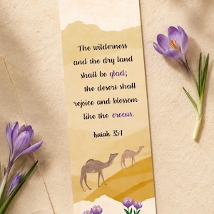 Könnte beinhalten: Ein rechteckiges Lesezeichen mit einer beigen und gelben Wüstenlandschaft, zwei Kamelen und violetten Krokusblüten. Der Text lautet: The wilderness and the dry land shall be glad; the desert shall rejoice and blossom like the crocus. Isaiah 35:1.