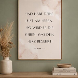 Könnte beinhalten: Ein rechteckiges gerahmtes Wandbild mit beigefarbenem Hintergrund, sanften Aquarell-Akzenten und dem schwarzen Text: UND HABE DEINE LUST AM HERRN, SO WIRD ER DIR GEBEN, WAS DEIN HERZ BEGEHRT! PSALM 37,4 in einer klaren, serifenbetonten Schriftart.