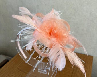 Tocado color melocotón con detalle de pluma en la diadema.