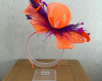 Tocado naranja con detalle de plumas rosas y moradas en la diadema.
