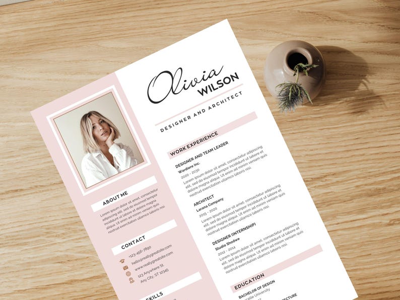 May include: A resume template with a photo of a woman, the name "Olivia Wilson", and the title "Designer and Architect". The resume has pink accents and sections for work experience, skills, and contact information. A small vase with greenery sits nearby.