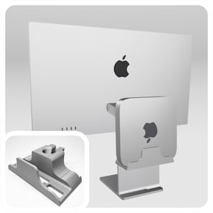 Könnte beinhalten: Ein silberner Computermonitor und ein silberner Computer. Der Monitor hat ein schwarzes Apple-Logo. Der Computer hat ein schwarzes Apple-Logo. Ein silberner Computerständer hält den Computer. Ein graues Computerteil befindet sich in der unteren linken Ecke.