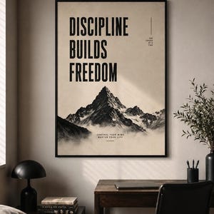 Może przedstawiać: Oprawiony plakat ścienny przedstawiający szczyt góry nad chmurami z tekstem DISCIPLINE BUILDS FREEDOM, ONE CHOICE AT A TIME oraz CONTROL YOUR MIND MASTER YOUR LIFE czcionką bezszeryfową na jasnobeżowym tle.