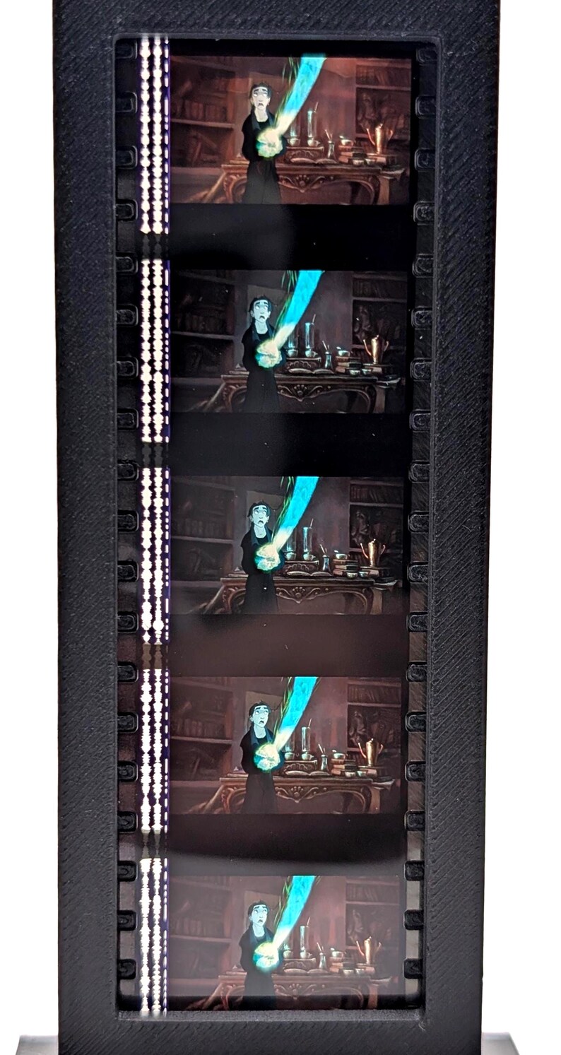 Puede incluir: Una pantalla de tira de pel&iacute;cula negra con cinco fotogramas de una pel&iacute;cula de animaci&oacute;n. Cada fotograma muestra un personaje de negro con un efecto azul brillante. La pantalla tiene un marco negro con una tira de luz vertical.