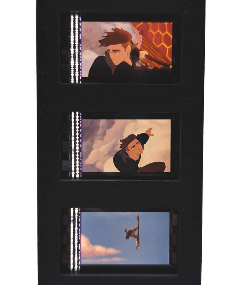 May include: A black film strip with three animated film cells. Each cell features a scene from an animated movie. The top cell shows a man with brown hair. The middle cell shows a man reaching up. The bottom cell shows a man on a board.